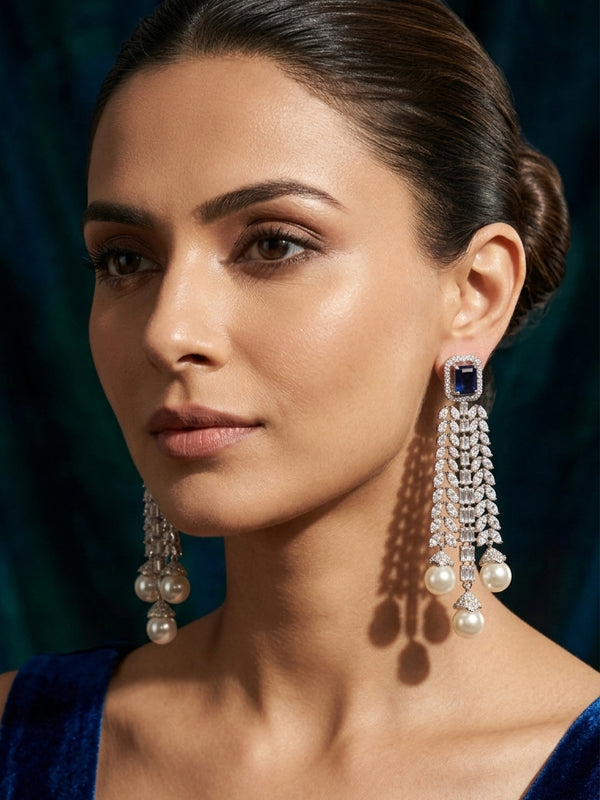 A pair of long, ornate dangle earrings with  dark blue stones , and ending in three white pearls,
