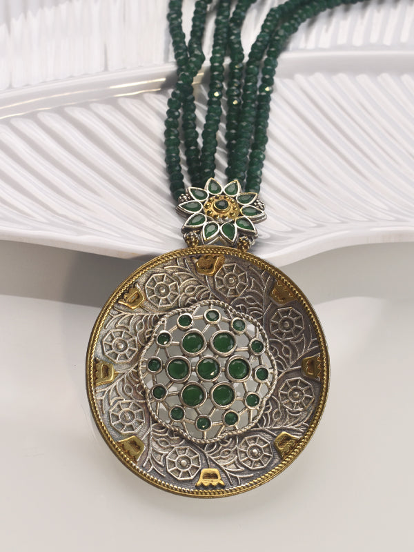  necklace with a large circular pendant featuring green gemstones 