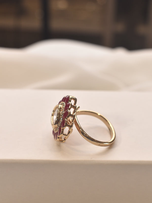 Gold ring with a red gemstone on a white surface