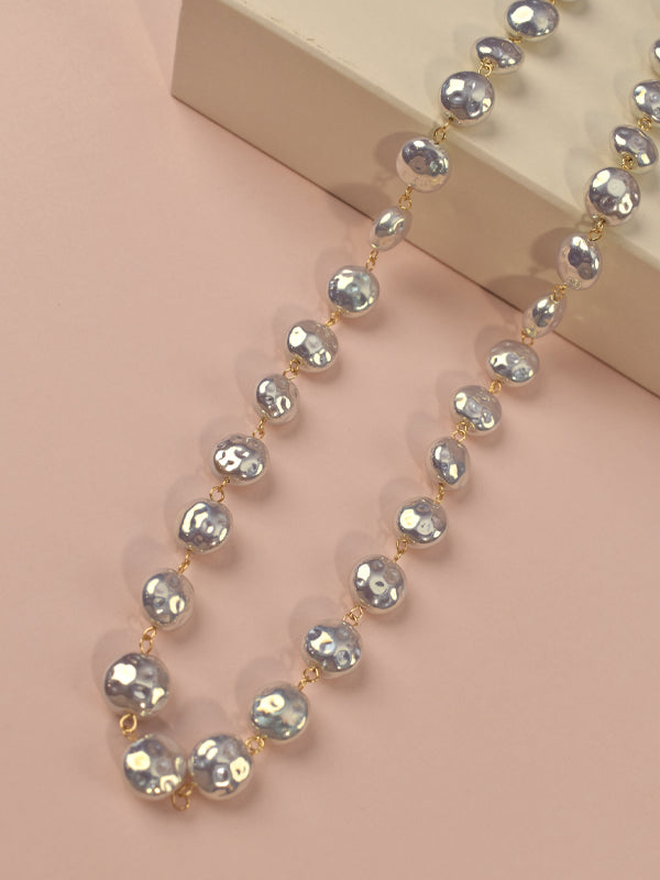A long strand necklace with faceted, irregular clear beads separated by small gold links