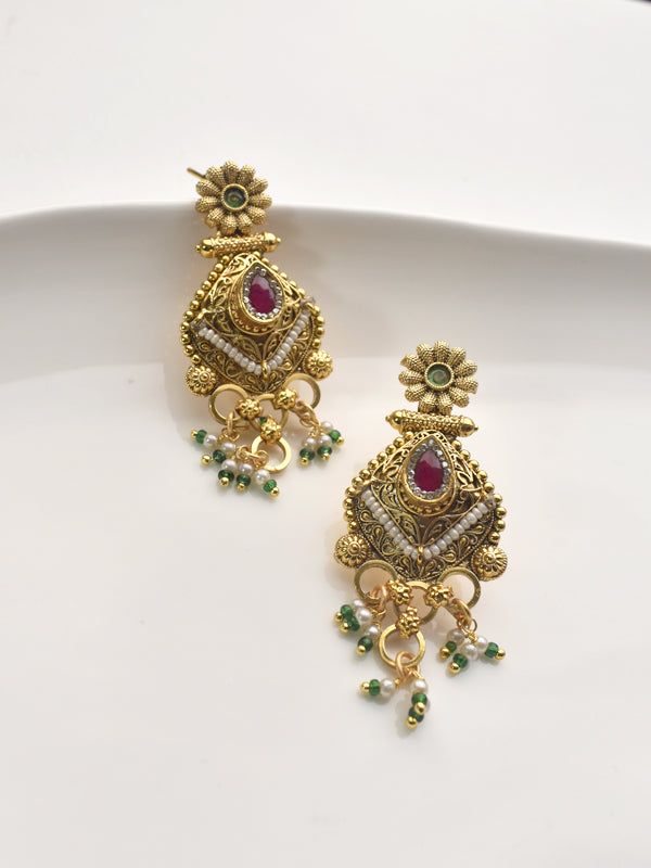 Golden earrings with red gemstones and green beads.