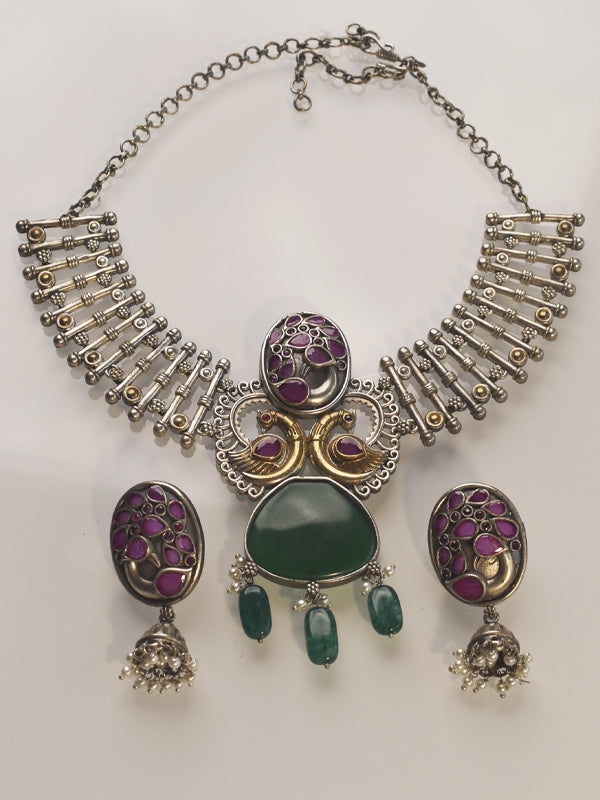 Ornate silver necklace with green and purple stones on a white background