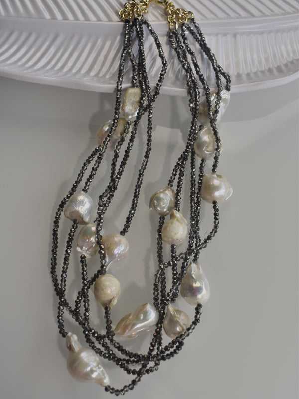 A layered pearl necklace with silver and gold-colored beads, 